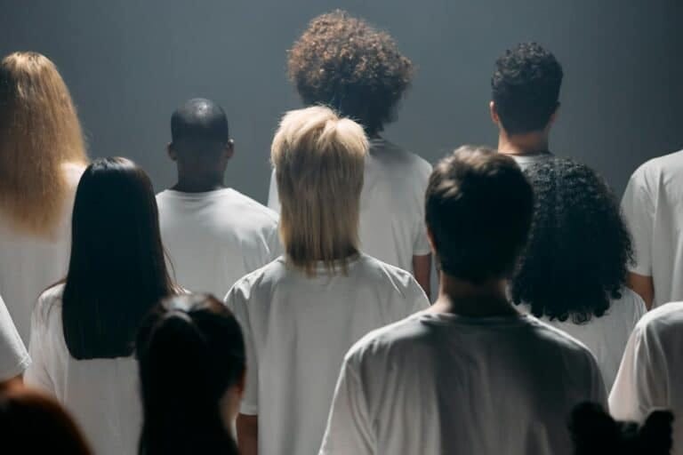 A diverse group of people seen from behind in a studio setting, emphasizing individuality and unity.