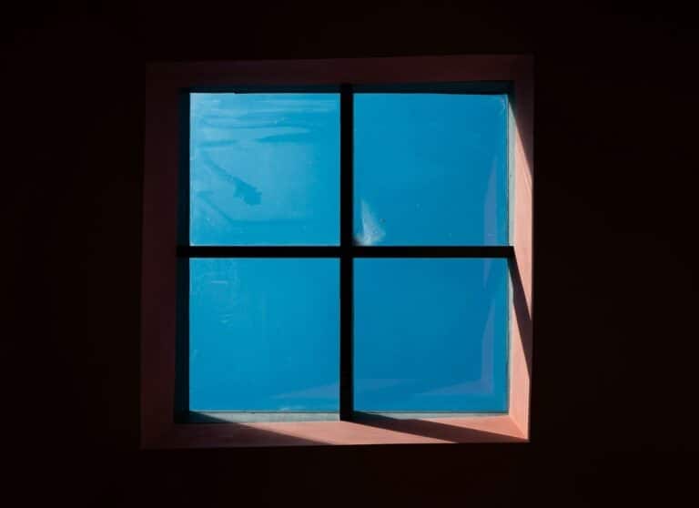 A window in a dark room with a blue sky
