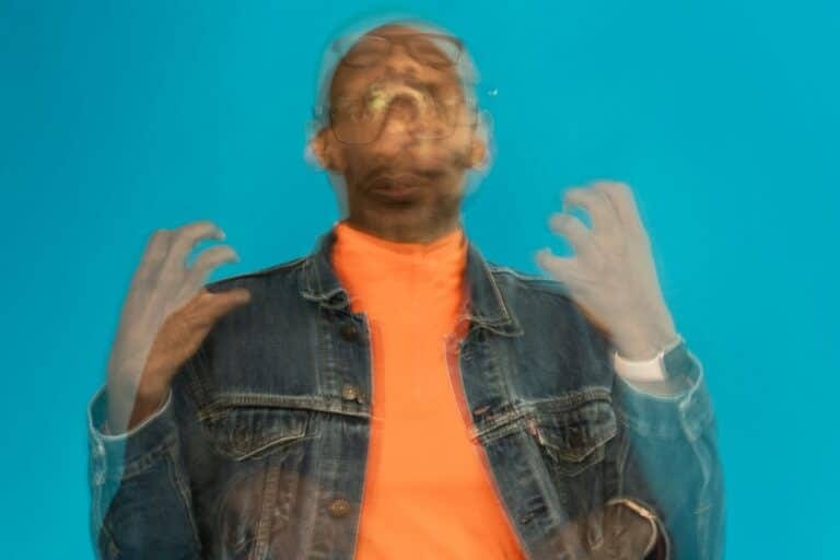 a man wearing a jean jacket and orange shirt