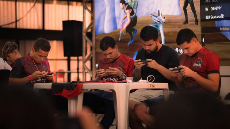 Four men playing mobile games at a table.
