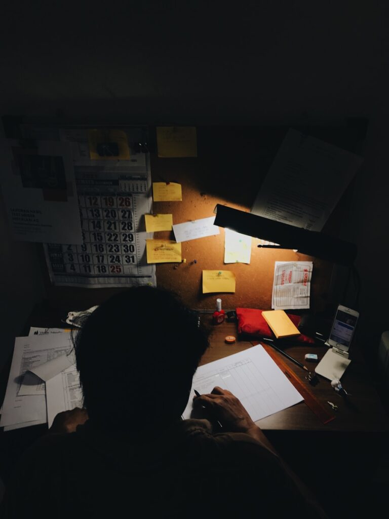 a person sitting at a desk in front of a lamp