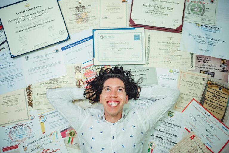 Happy man lying among numerous certificates and diplomas celebrating achievements.