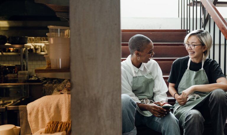 Two café employees enjoying a cheerful break and chat indoors.