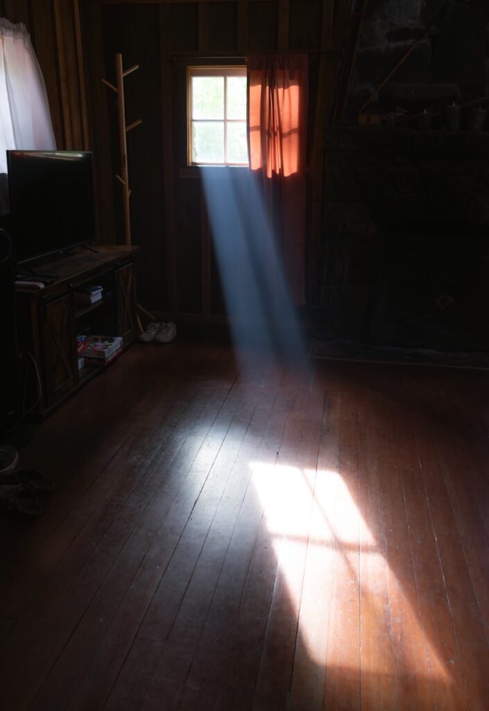 Sunlight streams through a window in a dark room.